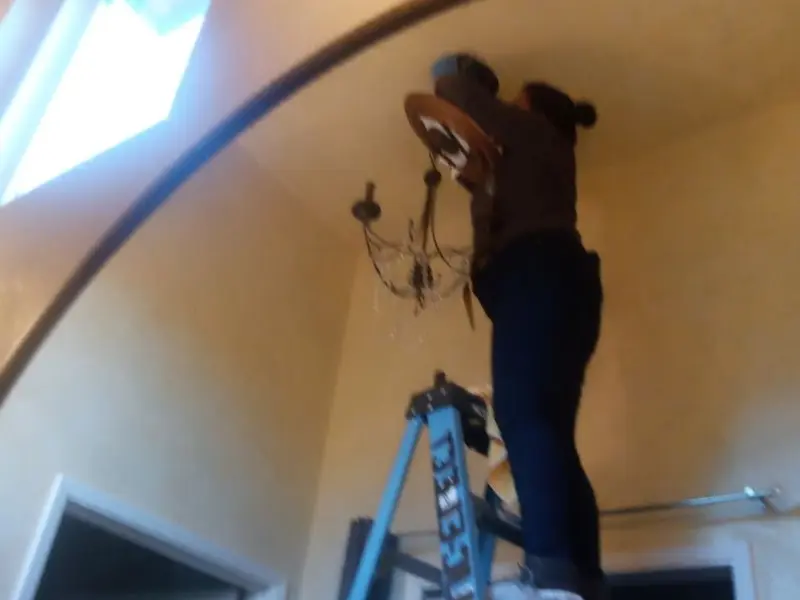 Electrician installing a chandelier in a South Weber residence
